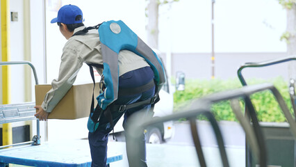 倉庫でパワーアシストスーツを使う作業員