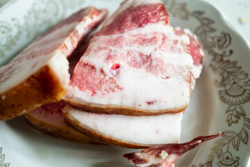 Sliced bacon on a plate. Pieces of salo with meat.