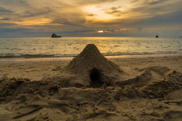 Pile of wet sand on the beach at sunset.