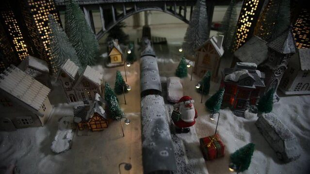 Miniature of winter scene with Christmas houses, train station, trees, covered in snow. Nights scene. New year in vintage toy city. Selective focus