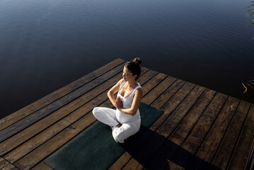 Pregnant woman doing yoga at lake during the day.