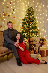 Obraz na płótnie Canvas Beautiful young couple sitting near christmas tree