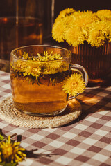 Dandelion flower healthy tea in glass teapot and glass cup on table. Delicious herbal tea from...