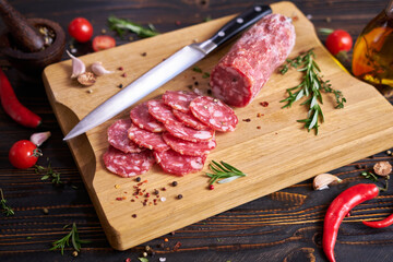 Traditional salami sausage on wooden cutting board with spices