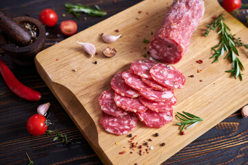 Traditional salami sausage on wooden cutting board with spices