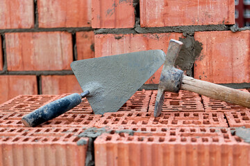 Construction trowel for laying bricks and blocks. Construction tool of a bricklayer. Hand working tool on the background of brickwork.