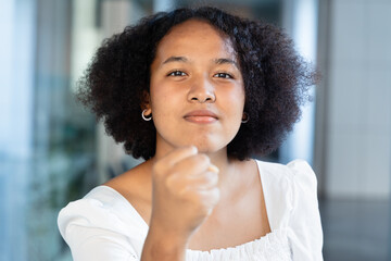 Aggressive angry upset young African woman raising fist to threaten you