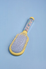 Yellow hairbrush with colorful balls on blue backgrouns.