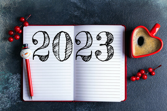 New year resolutions 2023 on desk. 2023 resolutions list with notebook, coffee cup, decorations on table. Goals, resolutions, plan, action concept. New Year 2023 background. Copy space