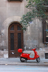 A red scooter is parked on the street in Europe, Spain, autumn