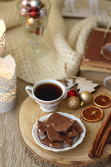 Various Christmas decorations, cup of tea or coffee, sweets, small presents, knitted blanket and candles. Selective focus.