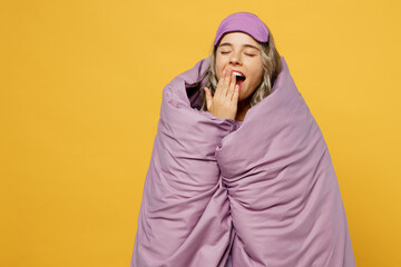 Calm young tired sleepy woman she wearing pyjamas jam sleep eye mask wrapped in duvet blanket yawn...