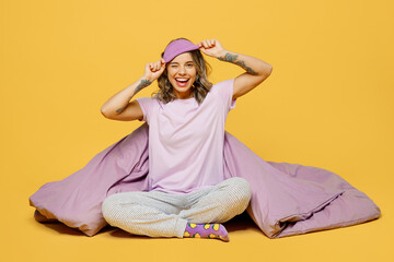 Full body young happy woman wears purple pyjamas jam take off sleep eye mask rest relax at home sit...