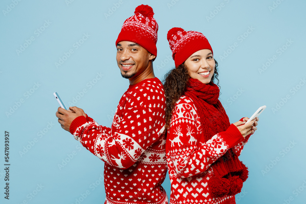 Wall mural sideways fun merry young couple two man woman wear red christmas sweater santa hat posing hold use m