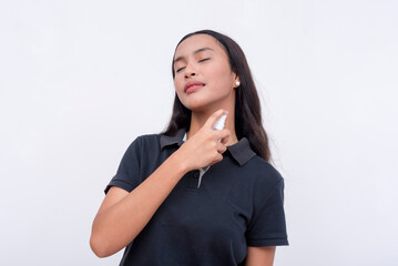 A young asian woman sprays light cologne on her neck. Isolated on a white background.