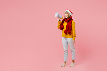 Full body elderly woman 50s year old wear knitted sweater red scarf Santa hat posing hold scream in megaphone announces sale isolated on plain pink background. Happy New Year Christmas 2023 concept.