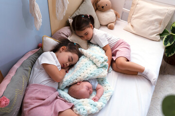 Three little siblings kids sleeping in bed at home, newborn baby with sisters.