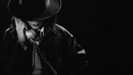 Dark noir portrait of a female detective holding a retro telephone receiver. Private detective,...