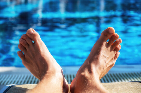 Gro&szlig;e F&uuml;&szlig;e eines Mannes auf einer Sonnenliege an einem Pool