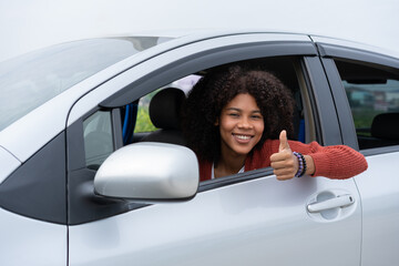 Young woman half asian half African shows thumb up inside of new modern car. Young woman excitement...