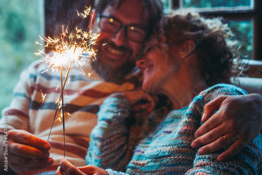 Wall mural romantic couple in love at home celebrate together with sparkler light in the night hugging and smil