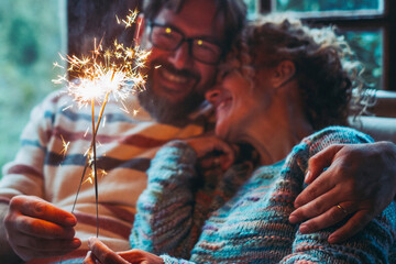 Romantic couple in love at home celebrate together with sparkler light in the night hugging and smiling each other. New year and anniversary event concept. Man and woman enjoy relationship celebrating