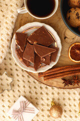 Various Christmas decorations, cup of tea or coffee, sweets, small presents, knitted blanket and candles. Flat lay.