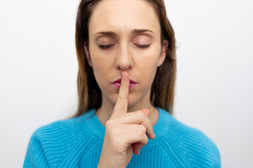 portrait of woman requesting silence with her hand or finger. silence peace or calm