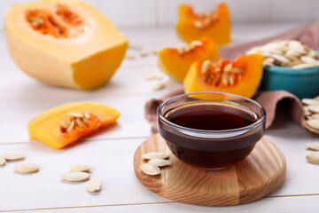 Glass bowl of fresh pumpkin seed oil on white wooden table