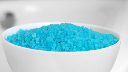 White bowl with light blue bath salt, closeup