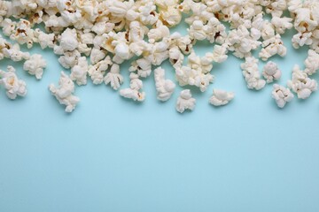 Tasty popcorn on light blue background, flat lay. Space for text