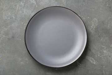 Empty ceramic plate on grey table, top view