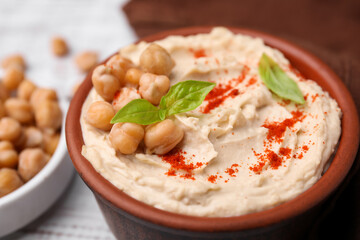 Delicious hummus with chickpeas and paprika served on white wooden table, closeup