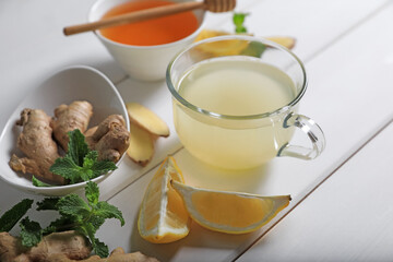 Delicious ginger tea and ingredients on white wooden table