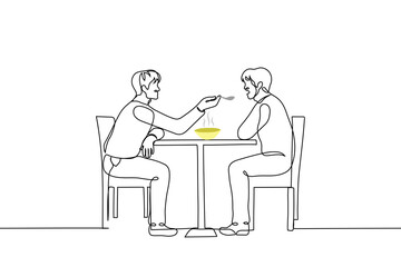 man sits at a table and feeds from a spoon another man sitting opposite him - one line drawing vector. concept of flirting homosexual men; feeding a person with a disability