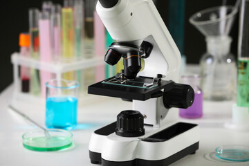 Modern microscope with glass slide on white table in laboratory, closeup