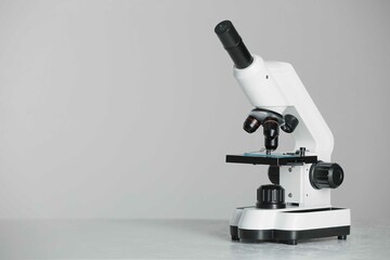 Modern microscope on grey background. Space for text