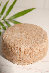 Solid shampoo bar on white wooden table, closeup