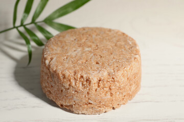 Solid shampoo bar on white wooden table, closeup