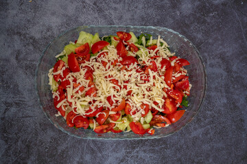 Vegetable salad with fresh cucumbers, tomatoes, olives, onions, lettuce and feta cheese. Healthy foods. top view.