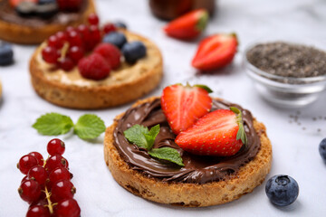 Tasty organic rusks with different toppings and ingredients on white table, closeup