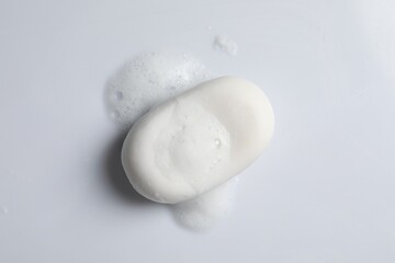 Fototapeta na wymiar Soap and fluffy foam on white background, top view