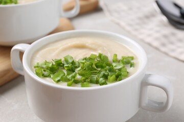 Bowl with tasty creamy soup of parsnip on light grey table, closeup