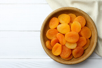 Bowl of tasty apricots and space for text on white wooden table, top view. Dried fruits