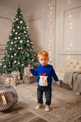 Naklejka premium New Year's photo of a little boy near a Christmas tree with gifts