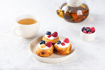 Traditional Russian, Ukrainian and Belarusian breakfast cheese pancakes with blueberries, raspberries and sour cream with cup of tea.