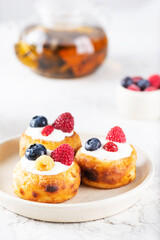 Breakfast cheese pancakes or syrniki with blueberries, raspberries and sour cream.