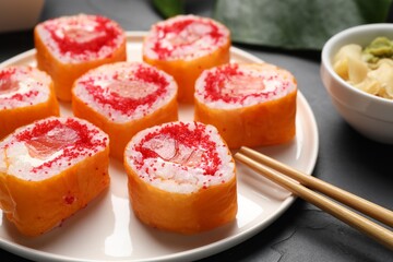 Delicious sushi rolls with salmon and tobiko on grey textured table, closeup