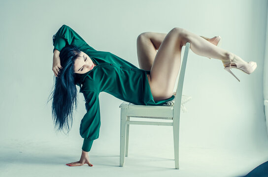 Semi-nude beautiful girl posing on a chair in a classic suit
