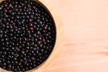 Tasty elderberries (Sambucus) on wooden table, top view. Space for text